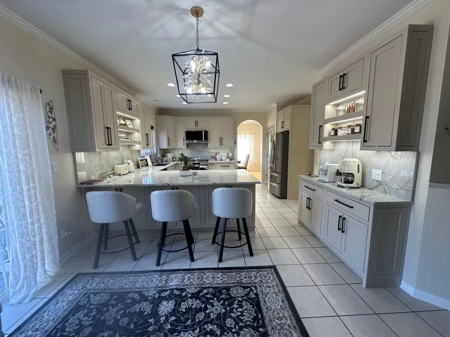 Custom light greige shaker kitchen with a waterfall marble island, slab backsplash, and built-in coffee station