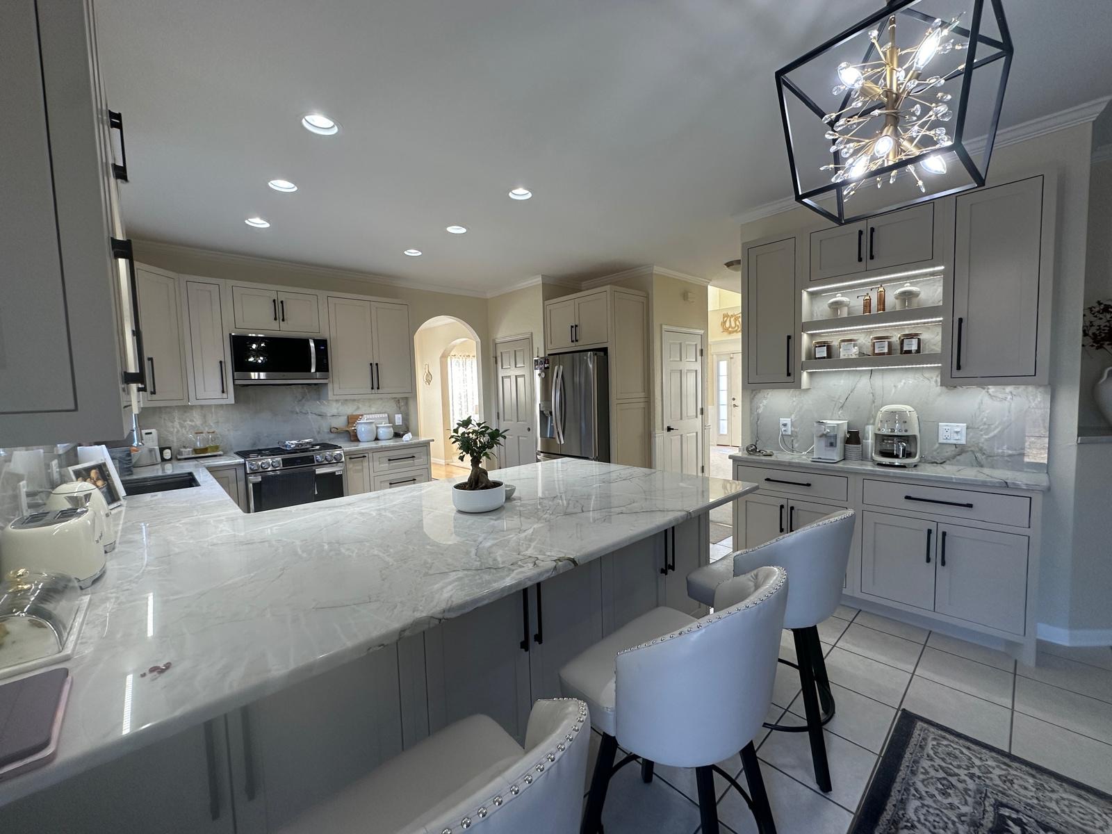 Custom kitchen with a marble waterfall island by AT Cabinetry