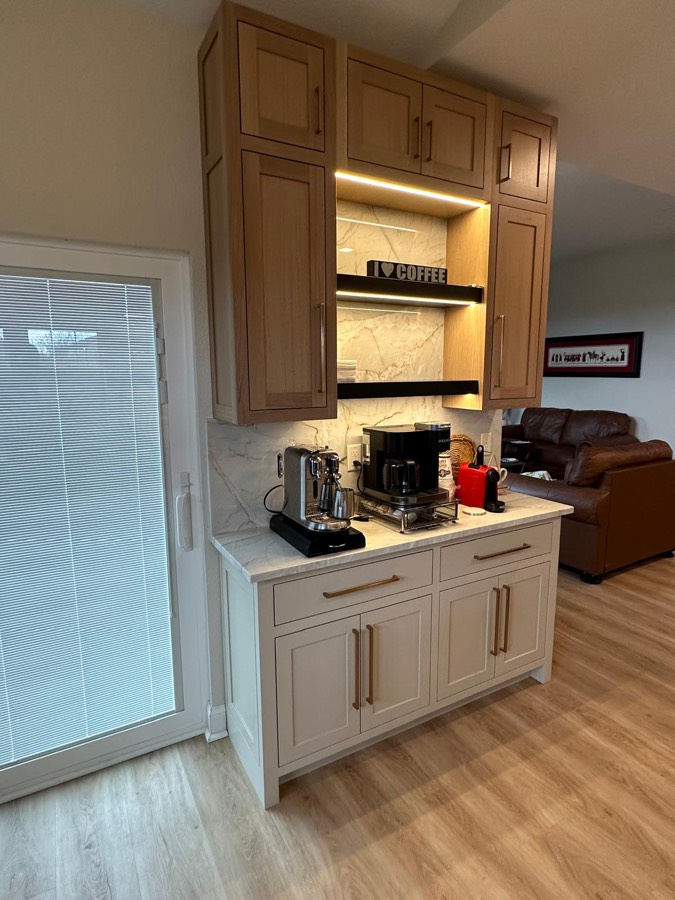 Close view of a coffee bar built-in with espresso machines on a marble countertop and warm accent lighting
