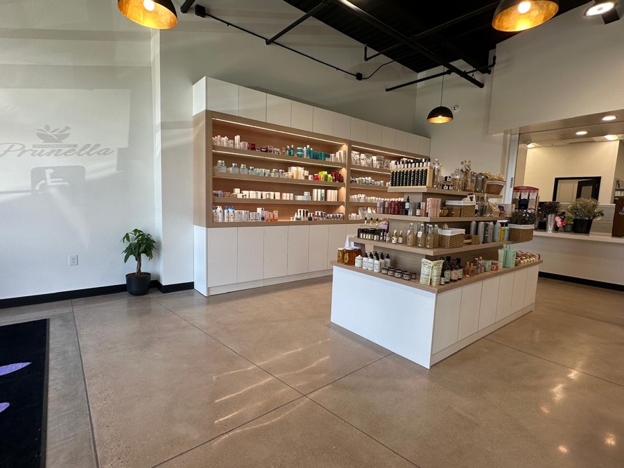 Custom white and light-wood retail millwork with backlit product shelving and a curved display island in a pharmacy
