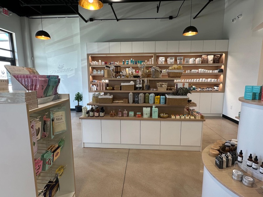 Long backlit white and wood retail shelving unit stocked with wellness and supplement products