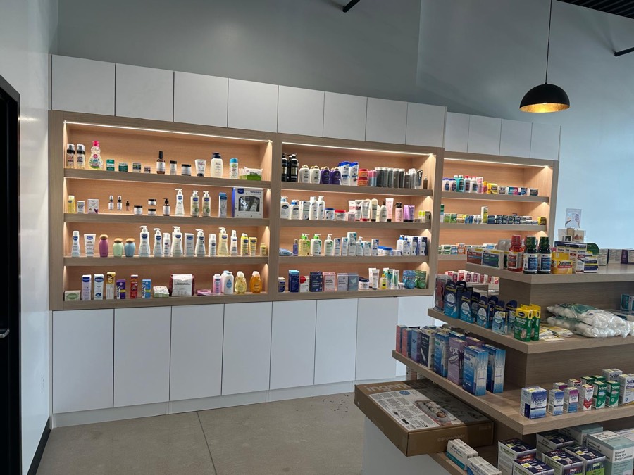 Backlit wood shelving wall set into white cabinetry with a tiered product display in the foreground