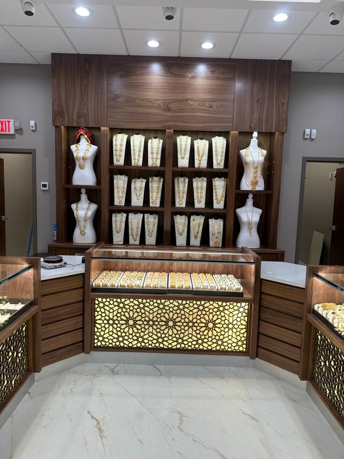 Walnut jewelry store feature wall with bust displays, tiered necklace shelving, and a geometric backlit case